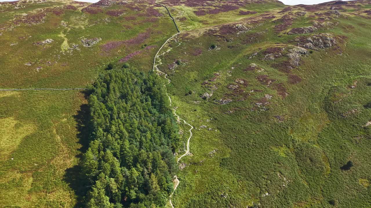 Drone ascending over a winding hiking trail on Gowbarrow Fell in the Lake District