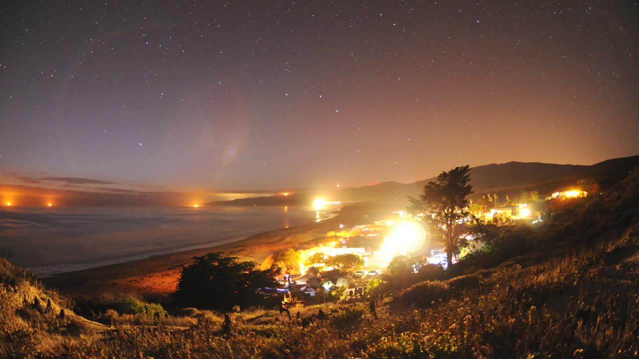 lapso de tiempo de rastros de estrellas y salida de la luna sobre el campamento de la playa de jalama en el condado de santa barbara california