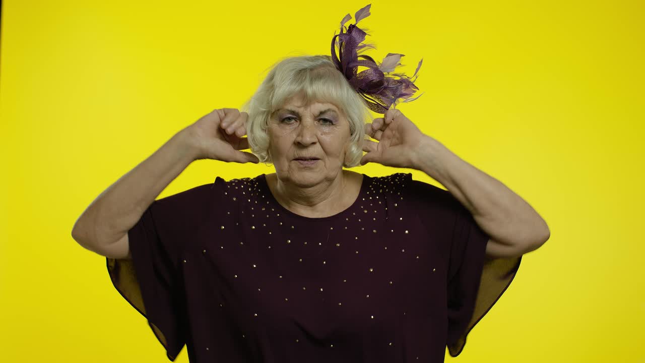 Donna anziana matura infastidita e irritata che si copre le orecchie e fa segno di no, evitando consigli e ignorando il rumore.