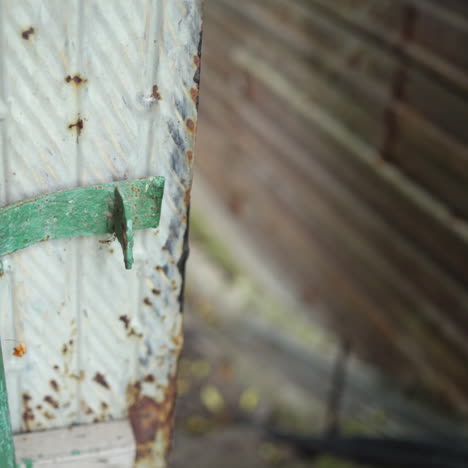woman's hands close grey gates with green bars and put metal lock. female hooks a steel lock on the old metal door gate outdoors. close-up.