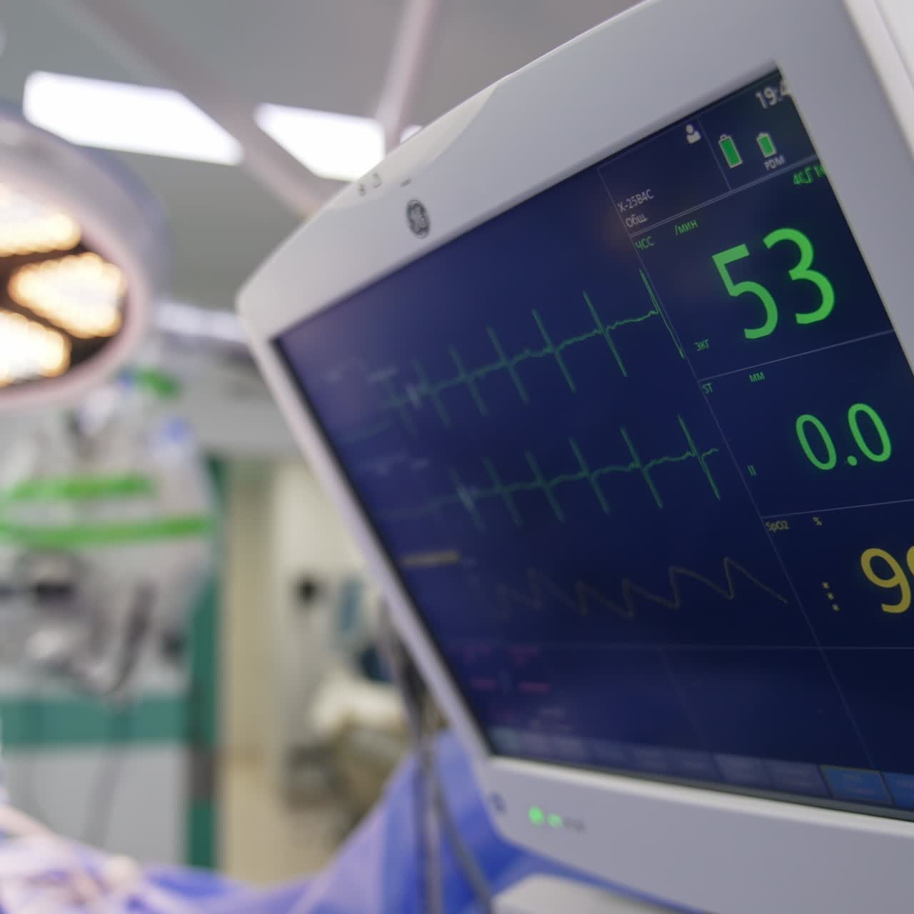 Little screen with life parameters working in surgery room during operation. Surgeons working in the room at backdrop in blur
