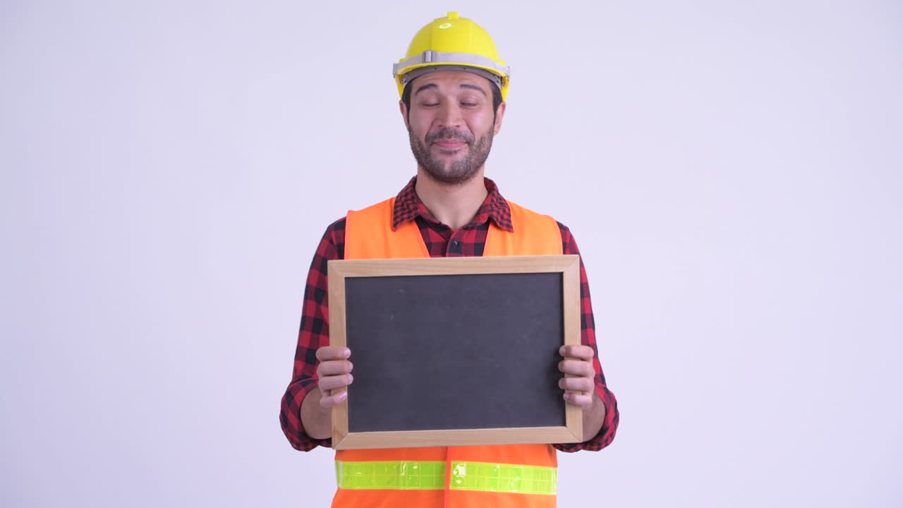 feliz hombre persa barbudo y guapo trabajador de la construcción con pizarra