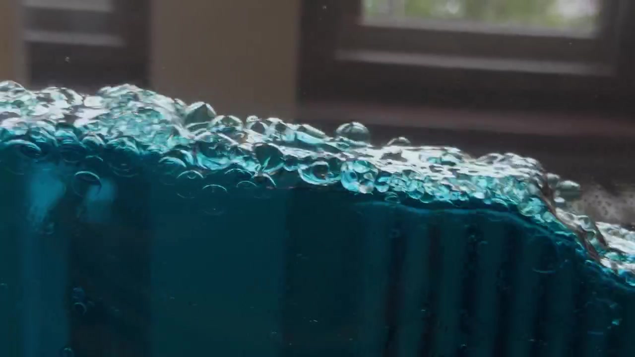 Bolle fluttuanti si muovono attraverso un'acqua blu vivido, creando uno sfondo astratto pulito con una fresca atmosfera acquatica