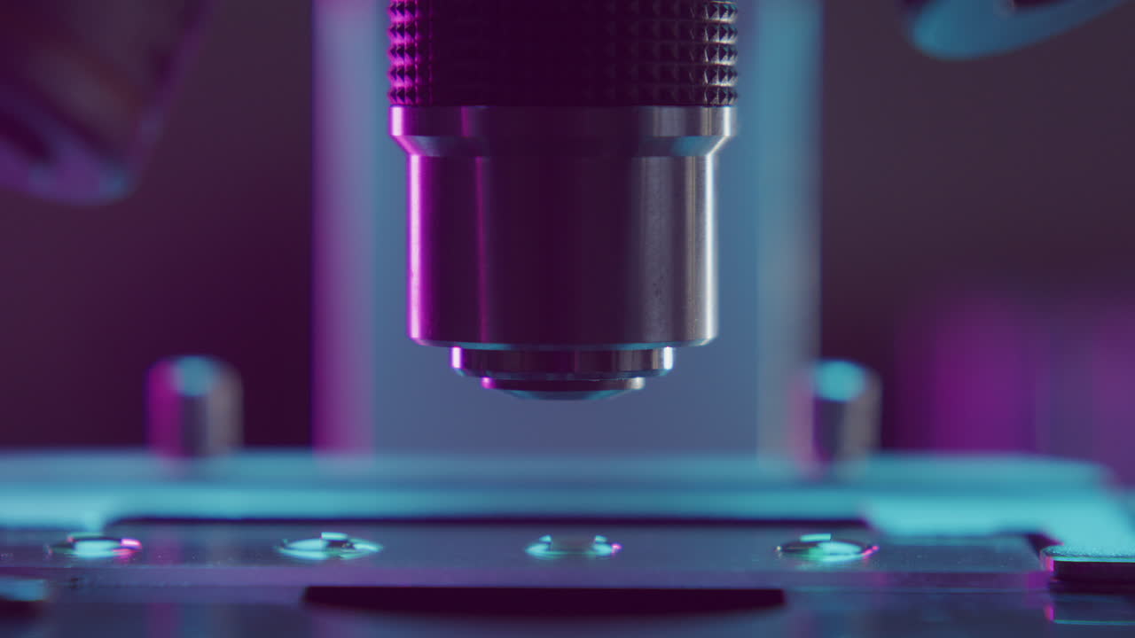 Close Up of Microscope Objective Lens Focusing above Specimen on Slide