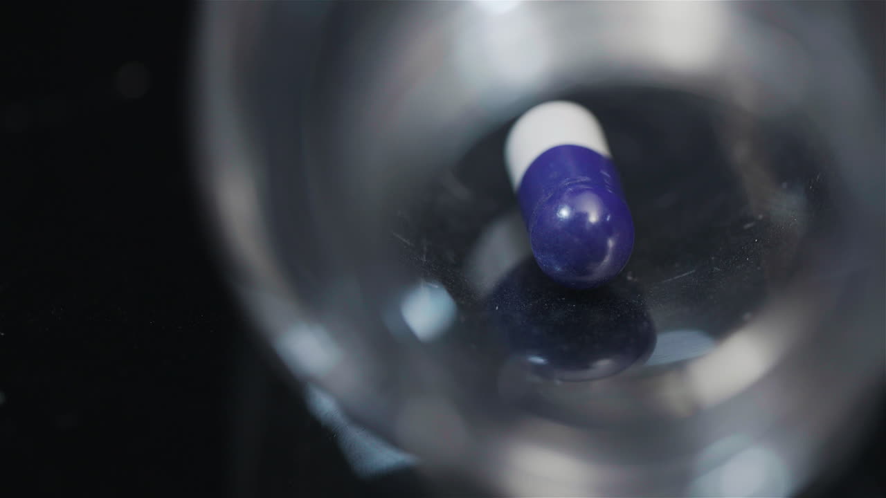 검정색 배경에서 회전하는 작은 병에 든 단일 의료 알약 5