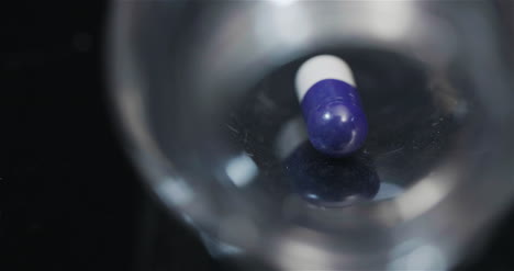 píldora médica única en botella pequeña girando sobre fondo negro 5