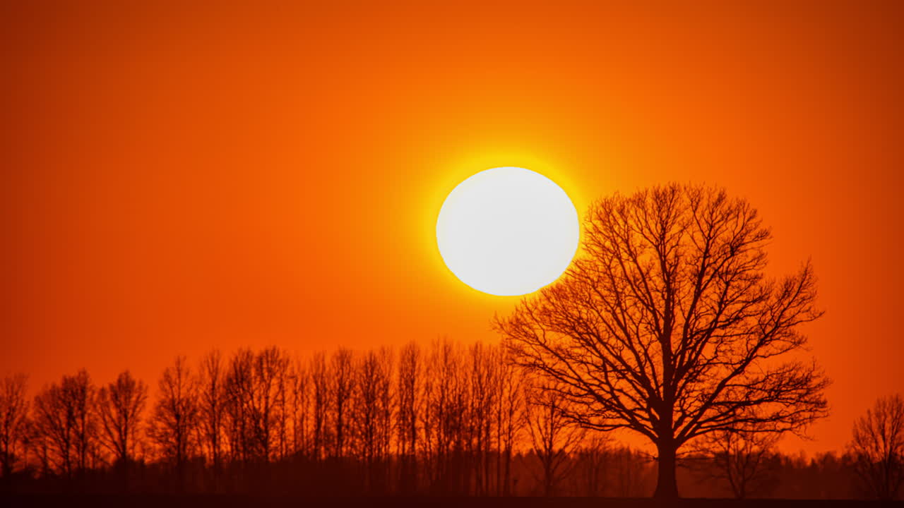 Sunset sundown sun disappearing in the horizon with yellow and orange warm colours, big bright setting with gradient colors