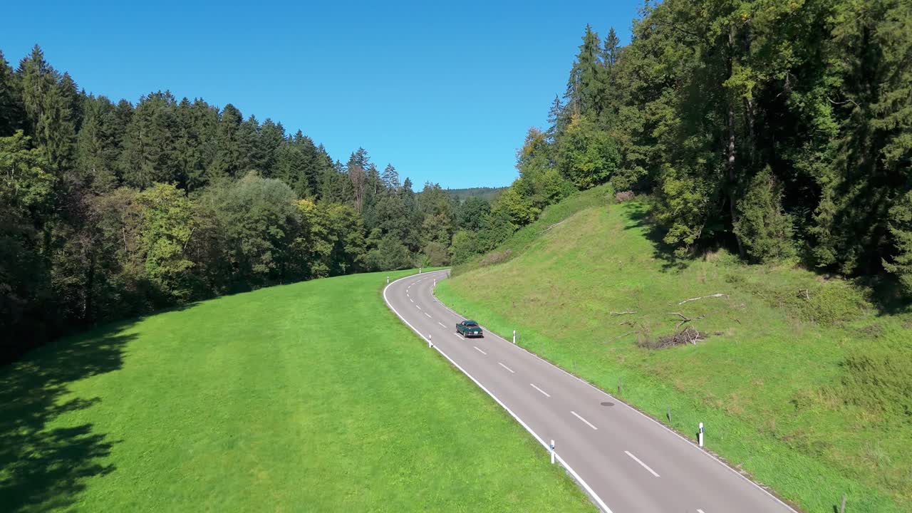 Drone follows a car along a winding countryside road in Zuzwil. Aerial