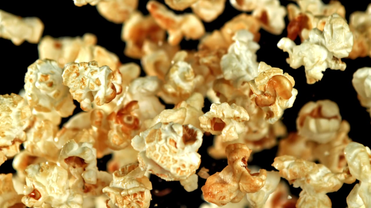 Pezzi di popcorn dorati che cadono e galleggiano al rallentatore.