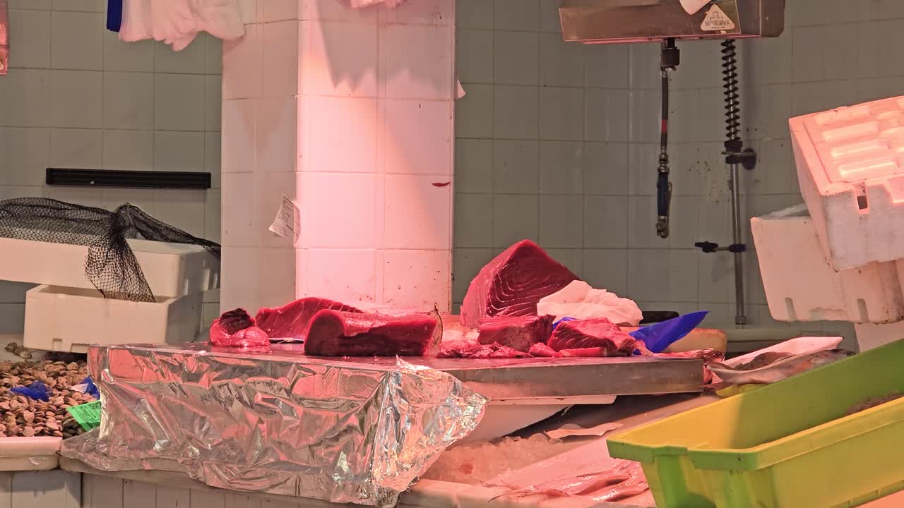 Fresh Almadraba bluefin tuna fillets and steaks displayed on a metal tray at a fish market stall, ready for sale
