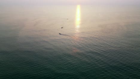 a stunning top drone view of boats scattered across the sparkling blue sea in goa, india, with the sun casting a golden reflection on the water, creating a peaceful and vibrant coastal scene.