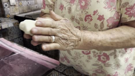 elderly hands shaping dough in a traditional kitchen with colorful tiles in a close-up shot