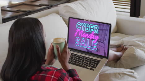 biracial woman using laptop at home for online shopping, slow motion