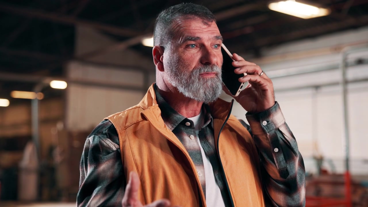 Uomo Maturo che Parla al Telefono in un Magazzino Industriale