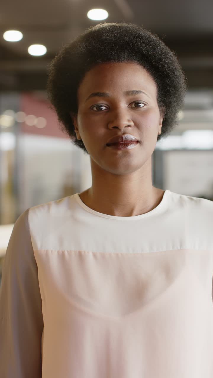 Vertical video of portrait of happy african american businesswoman in office in slow motion