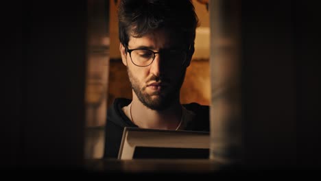 hombre tomando un libro de una biblioteca