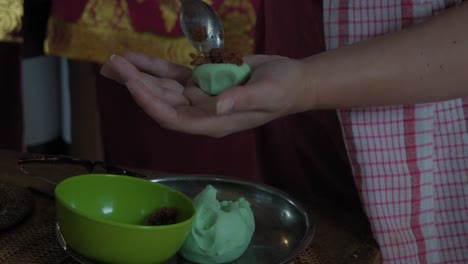 manos delicadamente la forma de klepon, un postre tradicional indonesio, en un entorno de cocina vibrante en bali