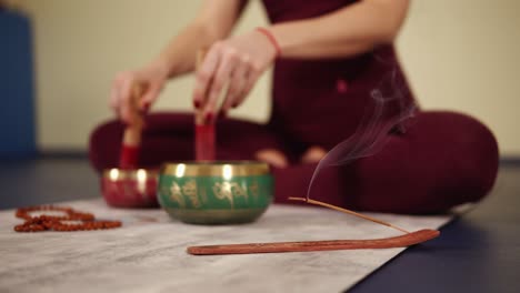 unfocused footage of scented stick mouldering while female hands are clattering on something.