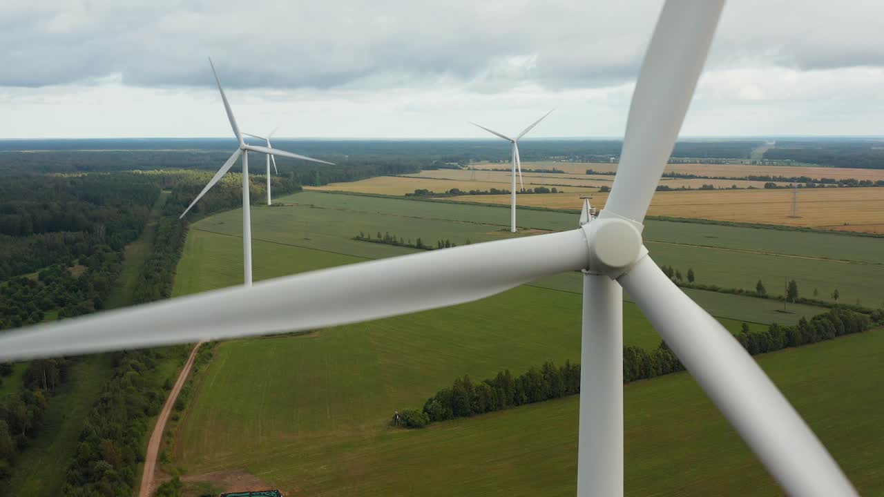 Close up of a rotating wind turbine with wind turbine park in the background