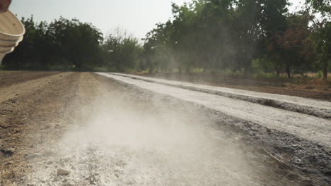 close up of the hand of a farmer spreading and throwing fertilizer to fertilize his farming field