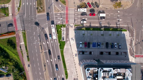 Top-down-aerial---over-a-city-road-intersection---smooth-urban-traffic-directed-by-traffic-lights---moving-in-the-city---departing-from-the-intersection,-turning-left-at-the-intersection