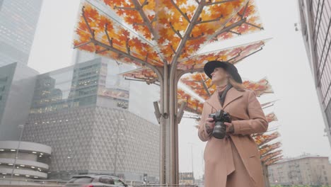 woman taking photo in the city with autumn-themed installations