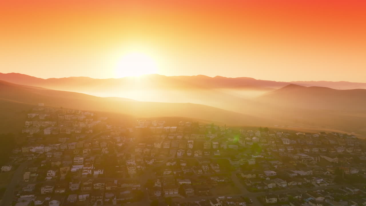 Inhabited area locating on the hills of California. Setting sun light covering the scene. Orange sky at backdrop. Top view.
