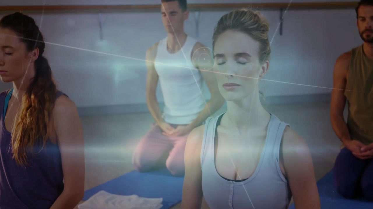 Group kneeling on mats and activating digital network overlays during guided meditation class