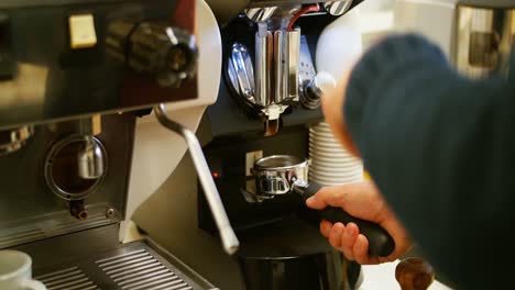 Man-holding-portafilter-filled-with-ground-coffee-in-cafe