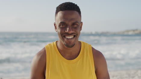 retrato de un hombre afroamericano guapo y en forma sonriendo feliz disfrutando de las vacaciones de verano en la playa usando un chaleco amarillo