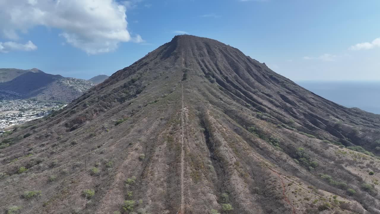 Aerial drone footage flying over the rim of Koko Head volcanic crater on Oahu, Hawaii, showcasing rugged cliffs, tropical landscapes, panoramic ocean views, and the island’s dramatic volcanic terrain