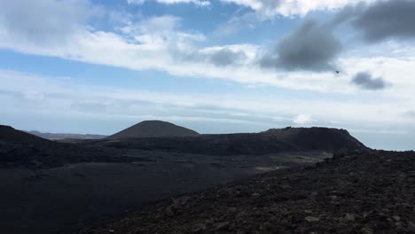 helicopter flying over volcano crater and lava field in iceland