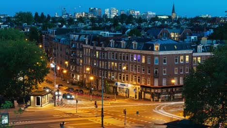 day-to-night timelapse of a cityscape in amsterdam, with a busy intersection in the foreground, a residential area and the zuidas business district in the background