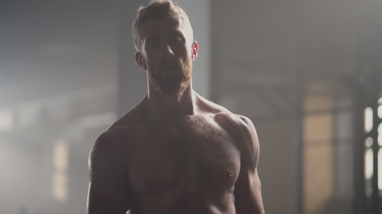 Beautiful Athletic man Wipes Sweat from His Forehead with a Hand Looks into Camera. He's Tired after Intensive Cross Fitness Exercise