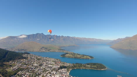 Paragliders-flying-over-Queenstown-and-Lake-Wakatipu-with-a-beautiful-mountain-background,-New-Zealand