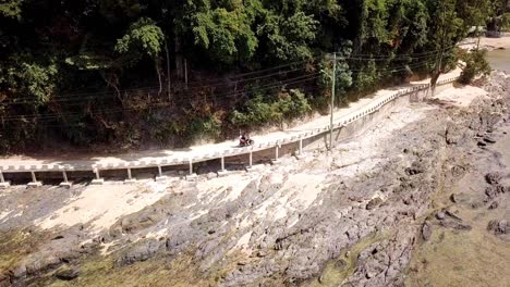 4K-Aerial-Drone-View-of-Couple-on-Motorcycle-Journey-Riding-Alongside-the-Beach-in-El-Nido,-Palawan,-Philippines