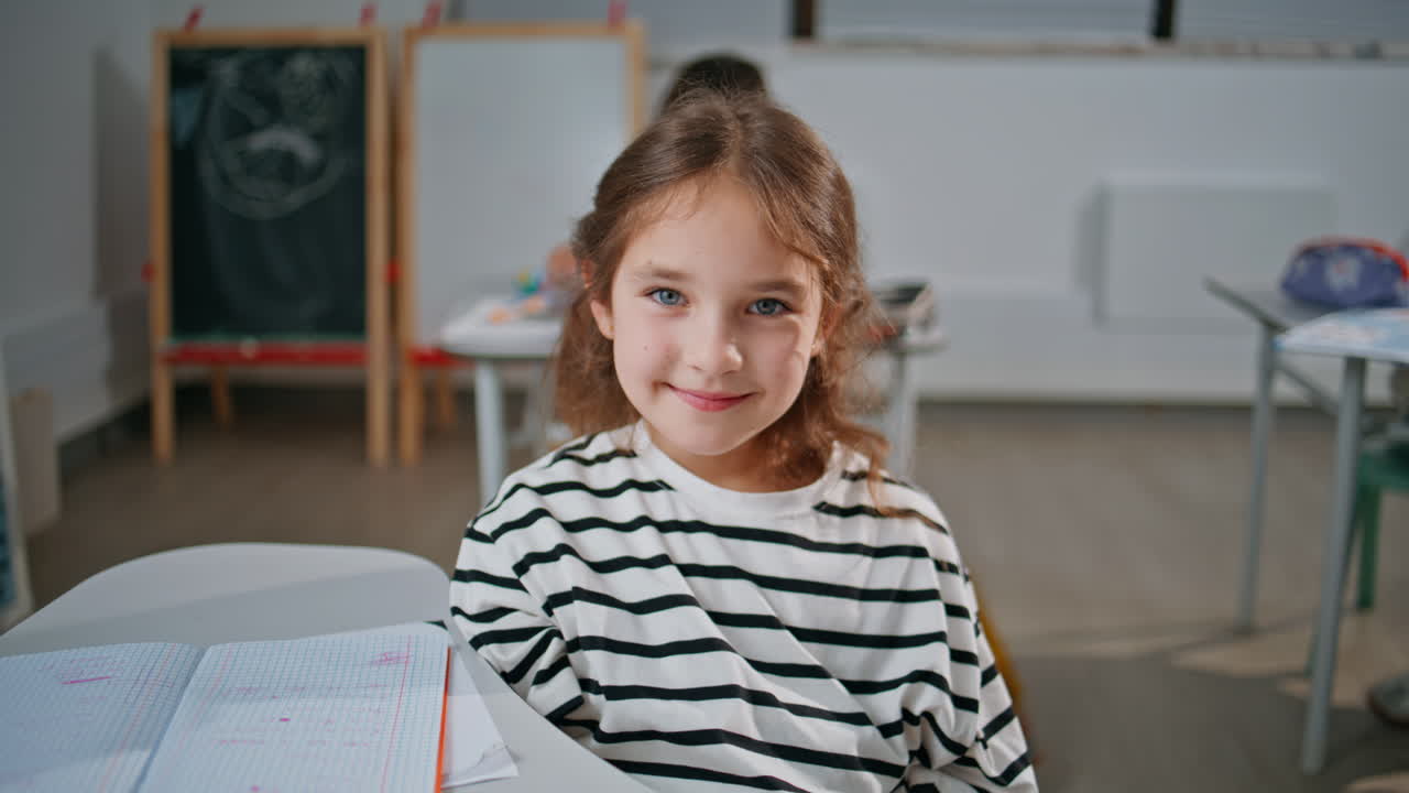 Primo piano di una studentessa sorridente che studia alla scuola elementare. Bambina che guarda la fotocamera