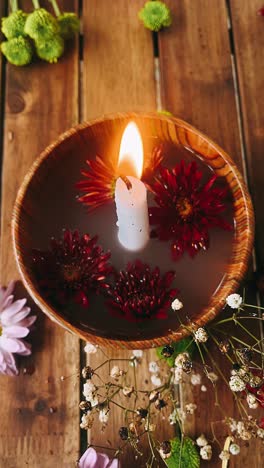 candle with flowers in a wooden bowl