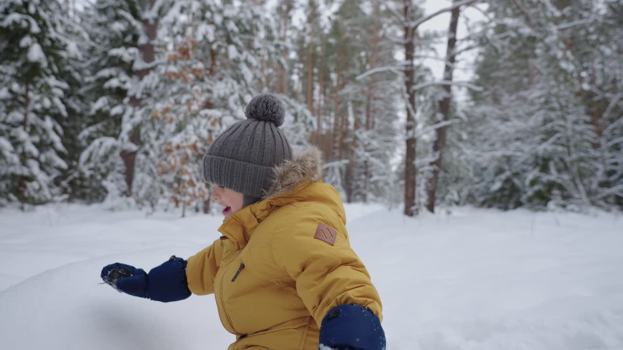 niño feliz está jugando en el bosque de invierno niño lindo con sombrero cálido y chaqueta está caminando en el parque