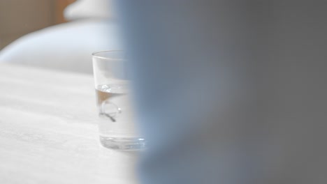 a hand placing a glass of water onto the table - close up