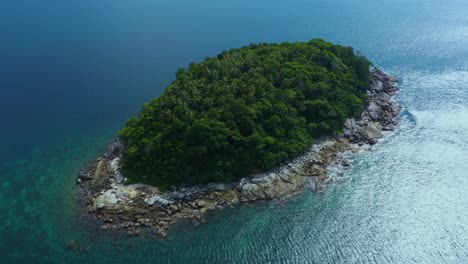 Fly-towards-tropical-island-with-stony-coast-and-green-forested-on-top,-palm-trees-crown-in-middle-of-dense-overgrown-thicket