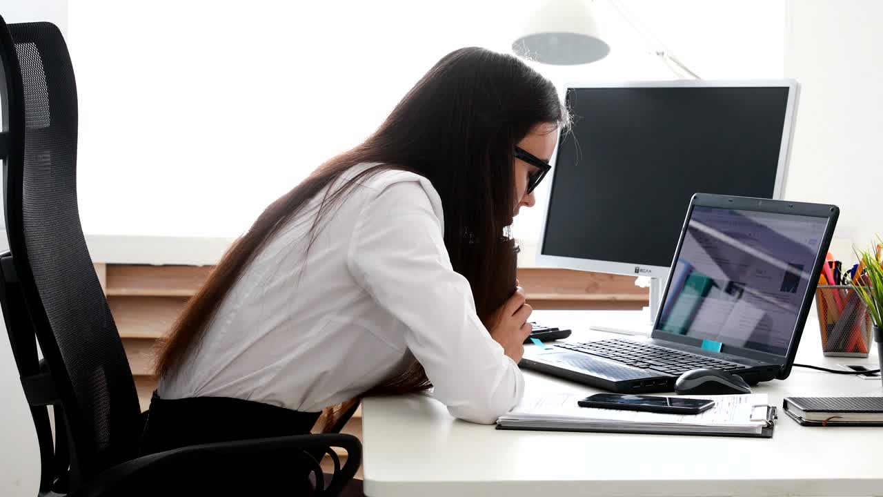 businesswoman setting aside cup and puting head on laptop