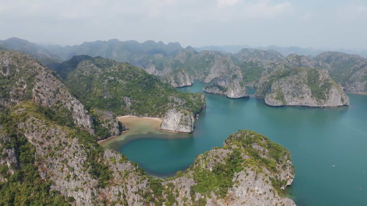 Cảnh biển rộng lớn từ trên không ở Cát Bà, Việt Nam với những hòn đảo đá vôi rải rác trên mặt nước yên ả dưới lớp sương mù nhẹ ban ngày.