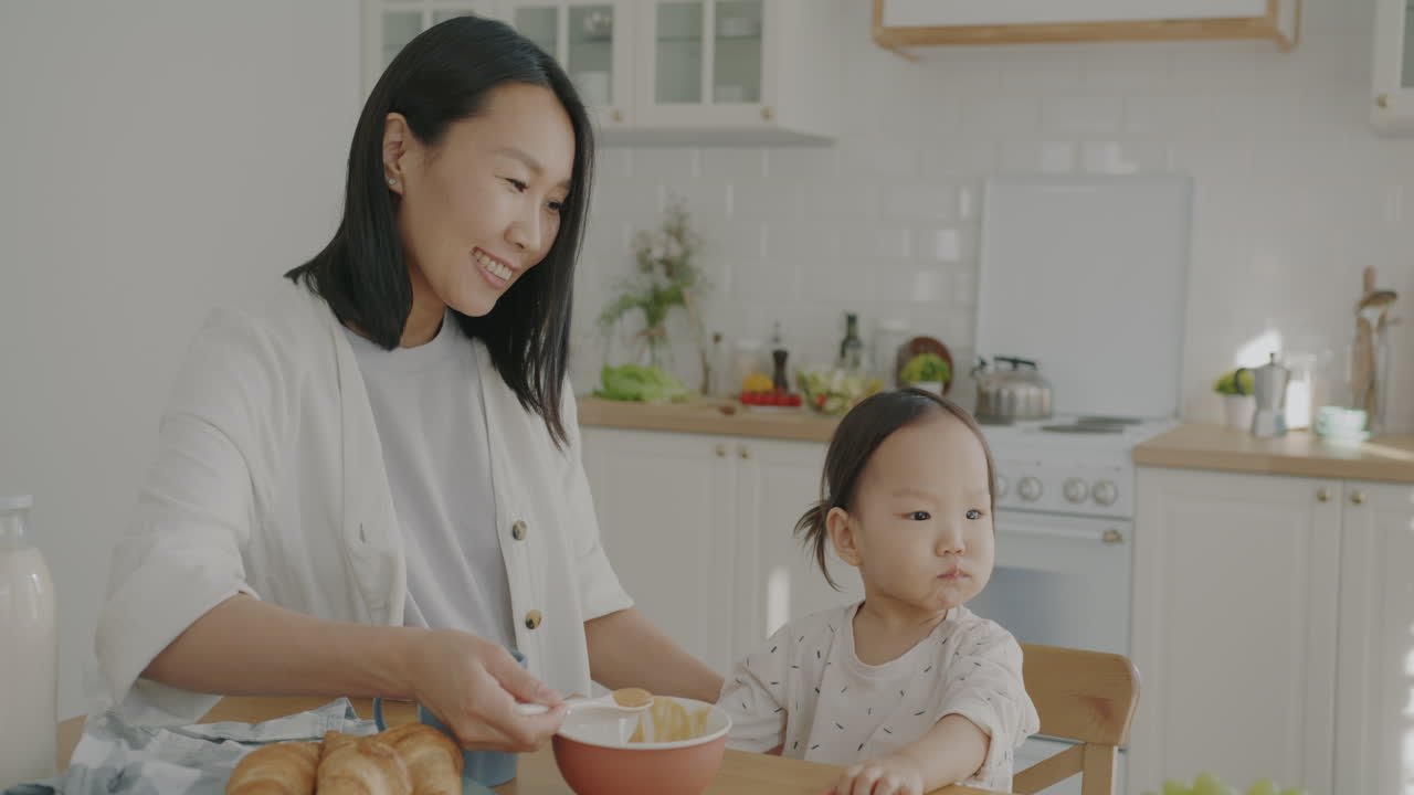 Mother feeding her baby breakfast in the kitchen