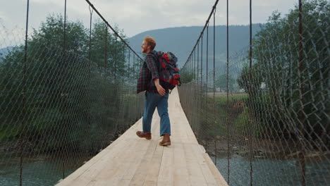 happy hiker enjoy traveling in mountains forest. joyful tourist jump on bridge.