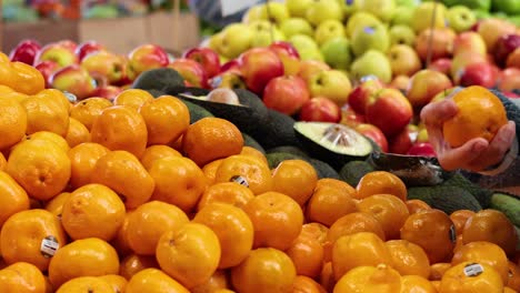 person, die orangen auf einem obstmarkt auswählt