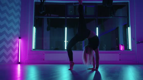 a woman dances in a studio with a neon light performing graceful exercises and movements from stretching and dancing in slow motion