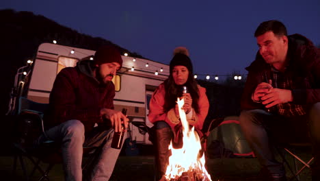 caucasian bearded man telling a story to his friends around camping fire