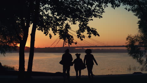 happy family silhouette run to river hold hands. beautiful bridge waterway view.