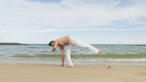 un tipo bailando capoeira en la playa.